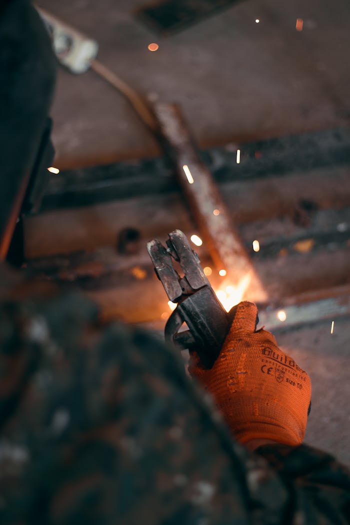 Close-up of a welder working with metal, showing sparks and safety gear.